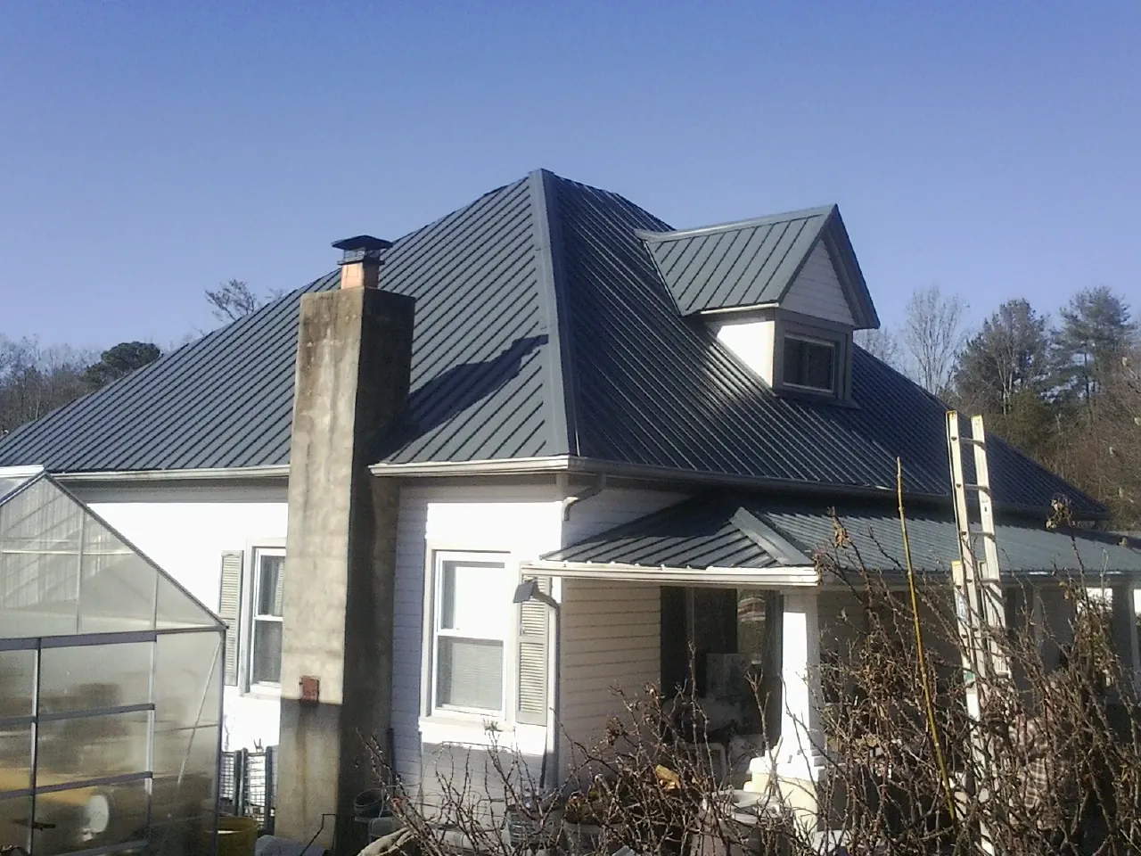Dark blue standing seam metal roof on a white farmhouse with dormer — Slate & Tile Roof Repair by Roofing Brothers in Isle