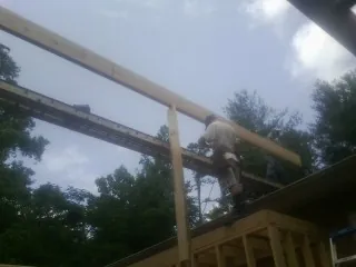 Carpenter setting a ridge beam over a new addition frame — Ice Dam Removal by Roofing Brothers in Isle