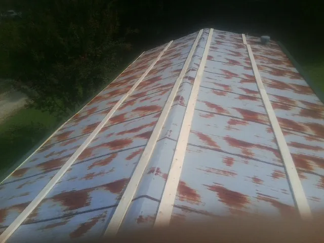 Rusted metal roof panels with new wood purlins before replacement — Storm Damage Roof Repair in Isle by Roofing Brothers