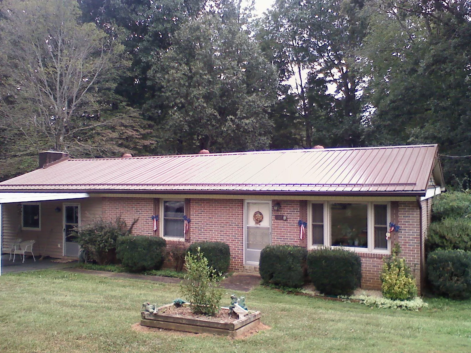 Bronze metal roof on a brick ranch home with a carport in Isle