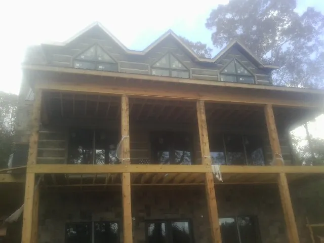 Dormers and porch framing on a large log home under construction — Roof Coating work by our crew in Isle