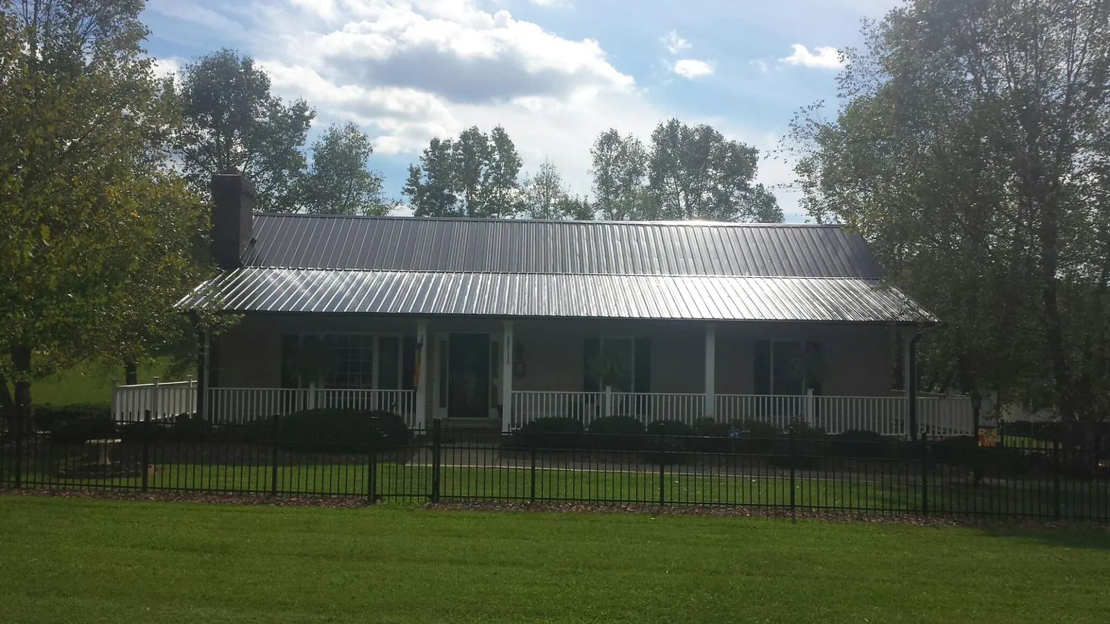 Gray metal roof on a brick ranch with a full width front porch — Gutter Guard Installation work by our crew in Isle