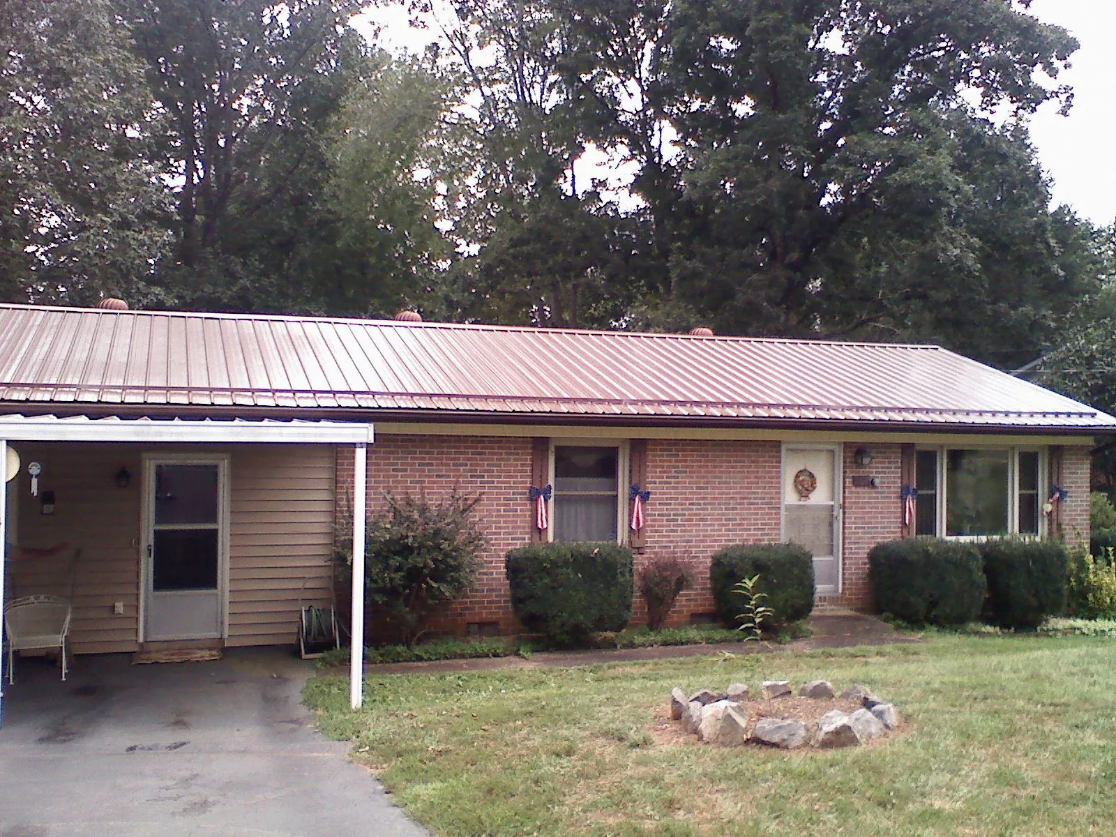 Bronze metal roof and carport on a brick ranch home — Roof Repair work by our crew in Isle